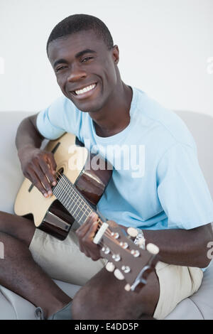 Casual man sitting on sofa playing the guitar Stock Photo