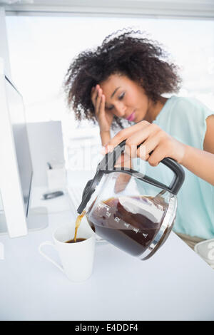 Tired businesswoman pouring a cup of coffee at desk Stock Photo