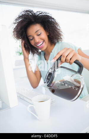 Tired businesswoman pouring a cup of coffee at desk Stock Photo