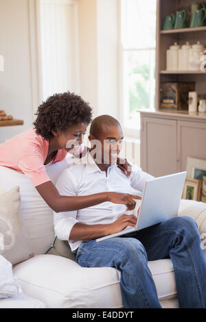 Happy couple relaxing together on the couch using laptop Stock Photo