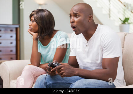 Bored woman sitting next to her boyfriend playing video games Stock Photo