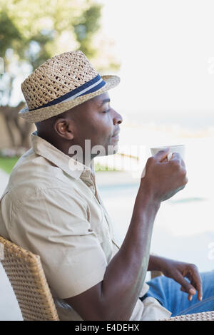Smiling man relaxing in his garden having coffee Stock Photo