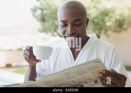 Handsome man in bathrobe having coffee outside Stock Photo