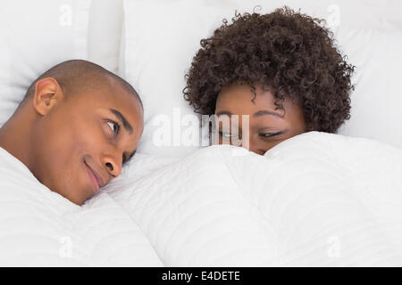 Happy couple lying in bed under the duvet Stock Photo