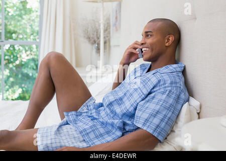 Happy man lying on bed and talking on phone Stock Photo