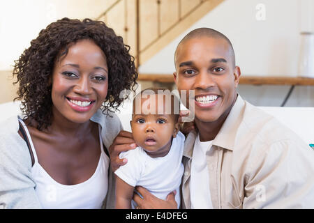 Happy young parents spending time with baby on the couch Stock Photo