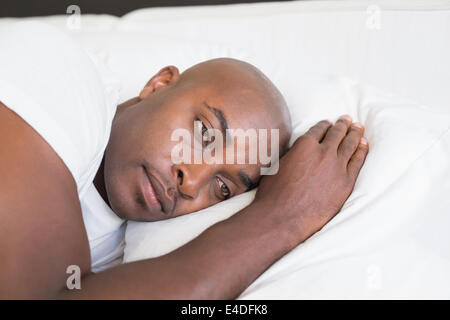 Unhappy man lying in bed Stock Photo