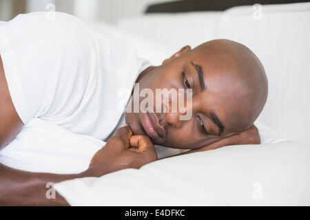 Unhappy man lying in bed Stock Photo