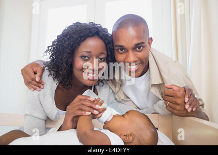 Happy parents feeding their baby boy in his crib Stock Photo