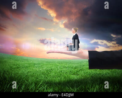 Composite image of businesswoman using laptop Stock Photo