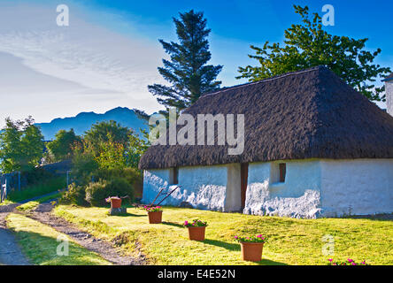 Old traditional thatched croft house in Plockton village, early morning sunshine, midsummer, Scottish Highlands, Scotland UK Stock Photo