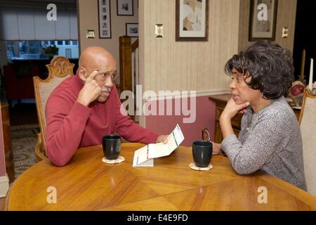 Senior middle class African-American couple discussing property tax invoice, bill. Stock Photo