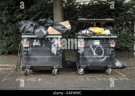 Large black communal wheelie bins overflowing with rubbish in Edinburgh's Marchmont area Stock Photo