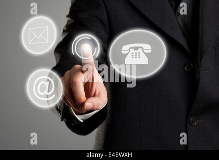 Businessman touching virtual futuristic display with icons for phone, mail and e-mail contact information Stock Photo
