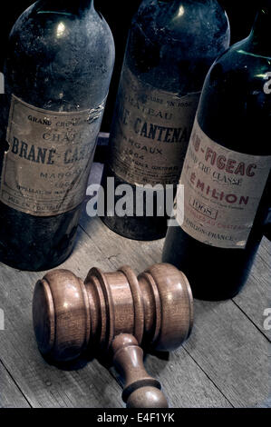 WINE AUCTION Bordeaux wine bottles vintage old dusty, Margaux and St. Emilion on wine barrel with auctioneers gavel in foreground Stock Photo