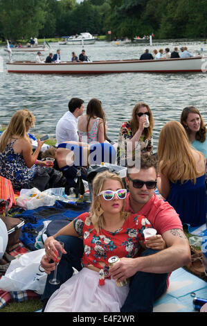 Henley on Thames Royal Regatta UK. Crowds of people watching the races from the river bank. Couple woman wearing white fashionable framed glasses and not watching the races, just hanging out and being seen to be there. 2014 2010s HOMER SYKES Stock Photo