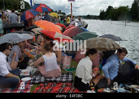 Rain raining picnic an English summer wet weather  2010s Henley Royal Regatta crowds of spectators line the banks and shelter un their umbrellas. UK 2014 HOMER SYKES Stock Photo