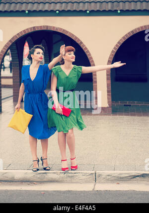 Two beautiful girls in retro style  hailing  taxi in the street Stock Photo