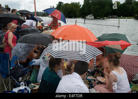 Rain raining picnic an English summer wet weather  2010s Henley Royal Regatta crowds of spectators line the banks and shelter un their umbrellas. UK 2014 HOMER SYKES Stock Photo
