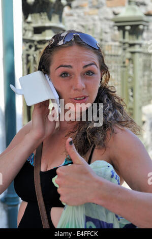 Woman using mobile phone and giving the thumbs up sign Stock Photo