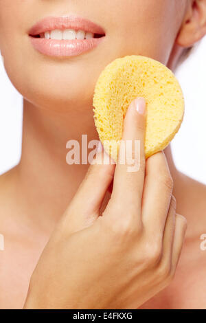 Young woman cleaning her face with sponge Stock Photo