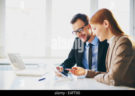 Image of two young business partners using touchpad at meeting Stock Photo