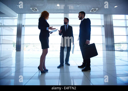 Group of three white collar workers interacting on background of office window Stock Photo