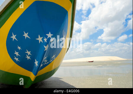 Fishing boat painted with bright Brazilian flag colors on the beach in Jericoacoara Brazil Stock Photo