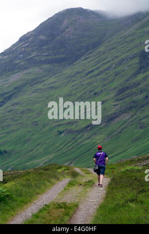 A young woman walking along a track in Glencoe, Scotland. Stock Photo