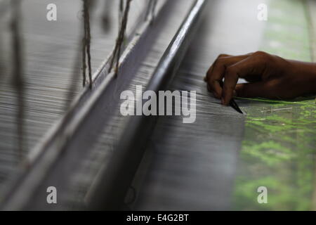 July 10, 2014 - Weavers weave famous Jamdani Saree.A sharee is the traditional garment worn by women in the Indian subcontinent. It is a long strip of unstitched cloth, ranging from five to nine yards in length, which can be draped in various style. The most common style is for the sari to be wrapped around the waist, with one end then draped over the shoulder.The Sharee boasts of the oldest existence in the world. It is more than 5,000 years old! Some people think that sharee is influenced by Greek or Roman toga, which we see on ancient statues. Although, there is no solid evidence and no c Stock Photo