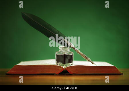 Quill pen and inkwell on old book Stock Photo