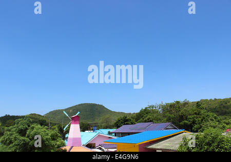 Wind turbine and colorful roof on a blue sky Stock Photo