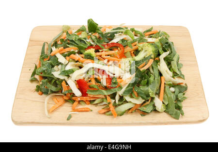 Mixed chopped stir fry vegetables on a wooden food preparation board isolated against white Stock Photo