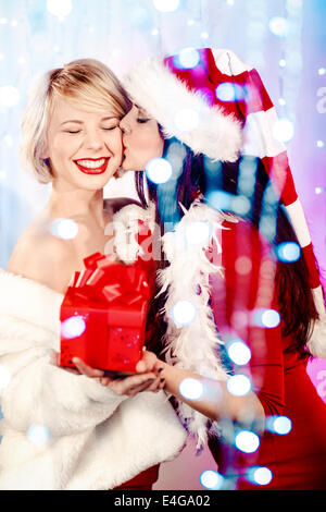 Young women in Santa Claus costume kissing Stock Photo