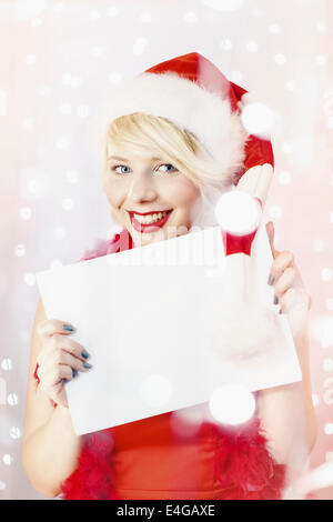 Young woman in Santa Claus costume holding empty list of wishes Stock Photo