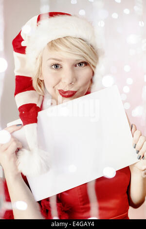 Young woman in Santa Claus costume holding empty list of wishes Stock Photo
