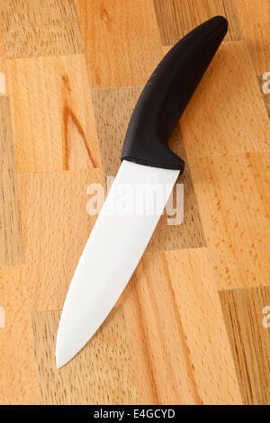 Ceramic knife with black handle on wooden cutting board Stock Photo