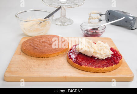 a victoria sponge cake sliced, jam spread, butter cream in place ready for spreading [Land] 'making a cake' (29 of 44) Stock Photo