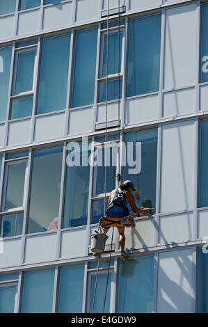 Male window washer cleaning the windows of a glass high rise condominium building in Vancouver, BC, Canada Stock Photo