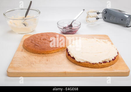 a victoria sponge cake sliced, jam spread, butter cream spread ready to put the top on  [Land] 'making a cake' (29 of 44) Stock Photo