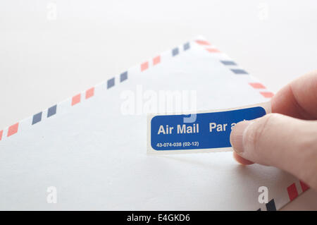 Putting air mail tag on envelope Stock Photo