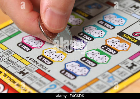 Coquitlam BC Canada - June 15, 2014 : Woman scratching lottery ticket called Monopoly. It's published by BC Lottery Corporation Stock Photo