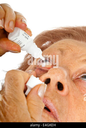 Elderly woman applying eye drops over white background Stock Photo