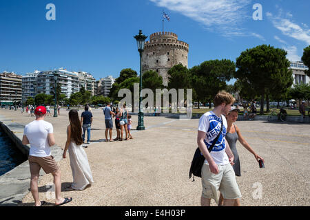Thessaloniki, Greece. 11th July 2014. Tourists walk in front of city's landmark, the White Tower, on the seaside promenade  in Thessaloniki, Greece. The Association of Greek Tourism Enterprises (SETE) increased its estimate for international tourist arrivals in 2014 to 19 million from 18.5 million last year. Thessaloniki, Greece on July 11, 2014. Credit:  Konstantinos Tsakalidis/Alamy Live News Stock Photo