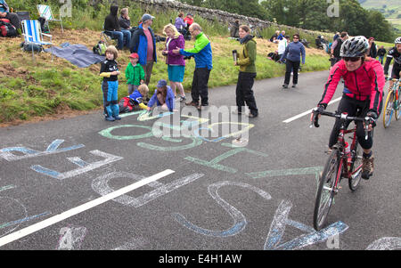 Children chalking riders names on the road before the arrival of the Tour De France near Hawes, North Yorkshire, England, UK Stock Photo