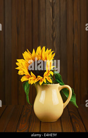 Still life with sunflower in vase on wooden background. Closeup. Stock Photo