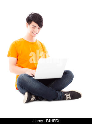 Smiling young student sitting on floor and  using laptop Stock Photo
