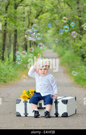 Portrait of a little boy with s suitcase in forest Stock Photo