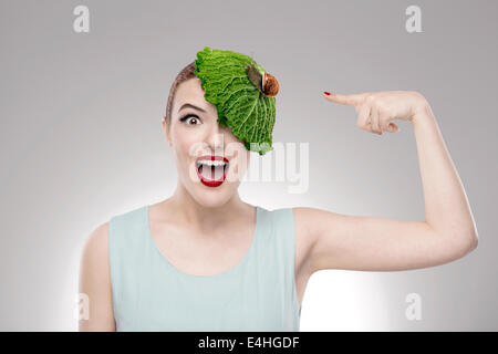 Portrait of a woman illustrating a vegan concept with a cabbage on the head with a snail on it Stock Photo