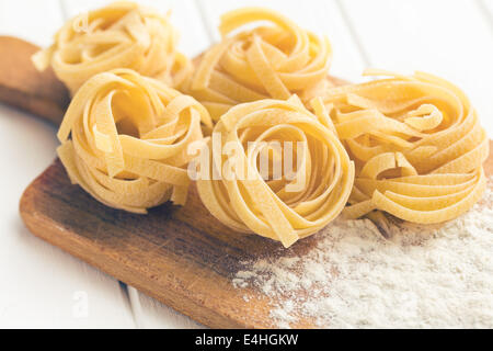 Italian pasta tagliatelle and flour on cutting board Stock Photo
